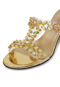 Sandal con tacco alto trasparente, con punta metallica dorata e dettagli intricati di strass gialli e verdi multifaccettati sulla parte superiore trasparente.