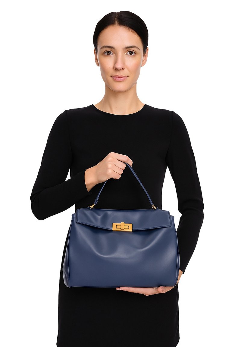 Sac à main en cuir bleu marine à la forme structurée, avec un fermoir en métal doré et une seule anse supérieure. Texture lisse et détail de rabat.