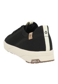 Sneaker nera in maglia con superficie testurizzata, suola bianca e accento riciclato. Presenta una toppa con logo marrone e un linguetta del tallone a contrasto.