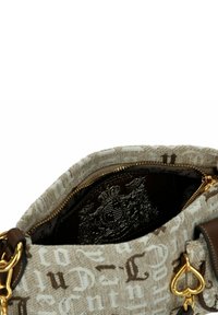 Bolso de tela beige claro con letras marrones, herrajes dorados y una correa de cuero marrón. El interior presenta un forro oscuro con un patrón de logotipo.