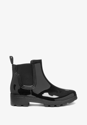 Botines negros brillantes con paneles elásticos en los laterales, puntera redondeada y suela de goma texturizada. El diseño incluye una lengüeta en la parte trasera.