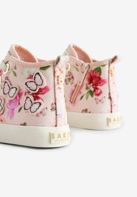 Różowe materiałowe sneakersy ozdobione kwiatowymi wzorami i aplikacjami motyli. Posiadają boczny zamek błyskawiczny oraz teksturowaną białą gumową podeszwę.