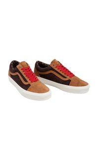 Zapatillas de ante marrón y negro con cordones rojos, suela de goma blanca y un patrón interior de cuadros. Diseño clásico de caña baja.
