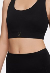 Black sports bra made of stretchy fabric, featuring a scoop neckline and a logo detail at the bottom. Seamless design with a fitted shape.