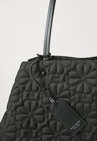 Black quilted handbag with a heart pattern, featuring a sleek leather strap and a black tag displaying "Kate Spade New York."