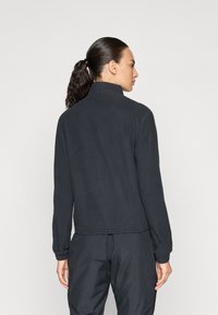 Svart zip-up jacka i mjukt material, med hög krage och elastisk nederkant. Med långa ärmar och åtsittande manschetter.
