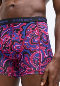 Több színű boxeralsók virágos paisley mintával. Az anyag sima, fekete derékpánttal, amelyen kék betűkkel olvasható a "BJÖRN BORG" felirat.