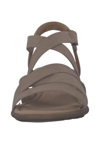 Beige sandaal met meerdere kruisbanden, gemaakt van glad materiaal. Heeft een ronde neus en een hielband met een verstelbare gesp. Platte zool.