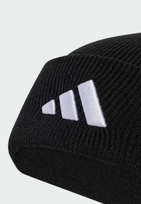 Czarna dzianinowa czapka beanie o prążkowanej fakturze z trzema białymi ukośnymi paskami naszytymi z boku.