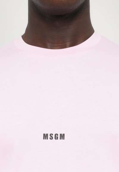Ružová bavlnená tričko s okrúhlym výstrihom a krátkymi rukávmi. Na prednej strane je umiestnené čierne logo "MSGM". Hladká textúra.