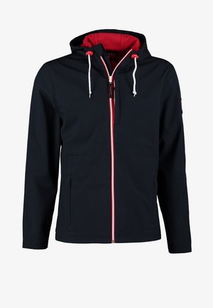 Mann trägt schwarze Jacke über weißem T-Shirt, schwarze Hose, bordeauxrote High-Top-Sneaker, trägt einen Camouflage-Rucksack über einer Schulter.