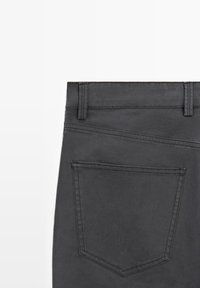 Ciemnoszare spodnie o klasycznym kroju z czterema kieszeniami, z widocznym przeszyciem i gładką fakturą, z naciskiem na detale talii i tylnych kieszeni.