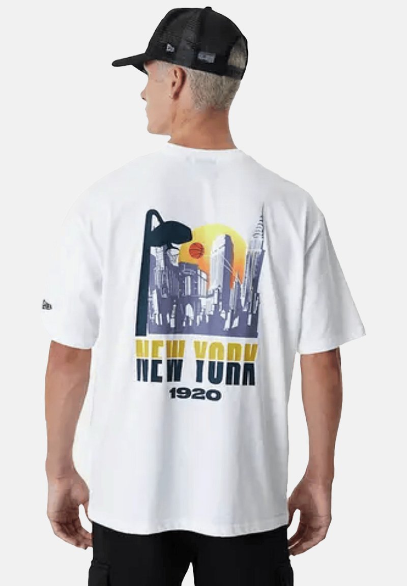 T-shirt bianca a maniche corte con una grafica dello skyline di New York in viola e giallo, con un sole e un pallone da basket. Materiale in cotone, vestibilità comoda.