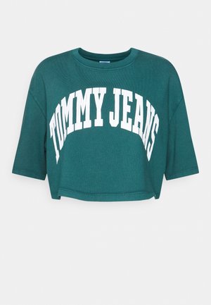 Krótki t-shirt w kolorze morskim z krótkimi rękawami i białym, łukowatym napisem „TOMMY JEANS” na przodzie.