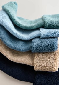 Set aus fünf gestrickten Textilmustern in verschiedenen Blautönen und Beige, mit glatten und strukturierten Oberflächen sowie gerippten Kanten.