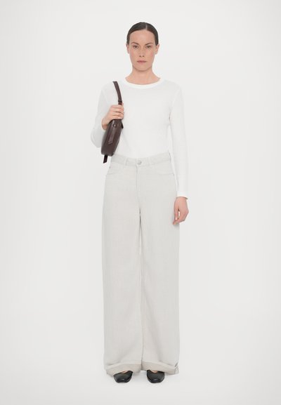 Lightweight, long-sleeve white top paired with loose, light gray trousers. Accessories include a brown handbag, complemented by black shoes.