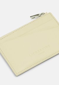 Żółty skórzany portfel na karty o gładkiej fakturze, z zamknięciem na zamek i wytłoczonym logo. Smukły design z kieszonkami na karty po jednej stronie.