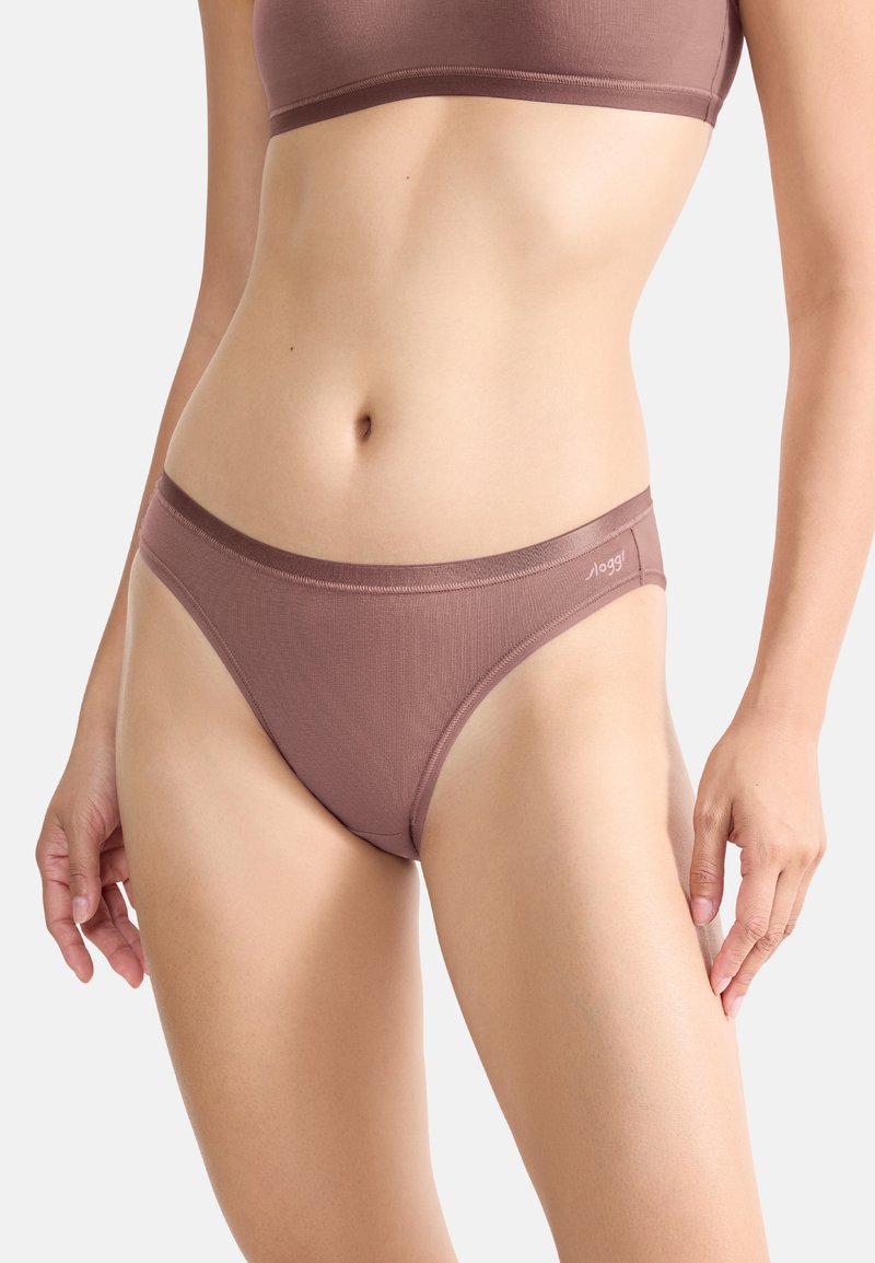 String en coton marron à côtes avec une taille lisse. Présente un branding discret sur le côté, conçu pour un ajustement confortable.