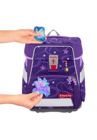 Mochila morada con parches de hada y unicornio, material texturizado, detalles en gris, patrones de estrellas, bolsillo frontal y correas ajustables.
