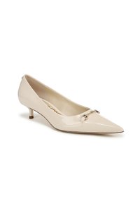 Escarpin en cuir verni beige avec un bout pointu, petit talon empilé et un décor en métal au niveau du cou-de-pied. Fini lisse et brillant.