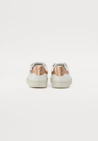Hvite sneakers med en metallisk roségullakcent på hælen, glatt lærtekstur, og lavt design med gummisåle.