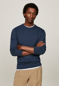 Maglione blu navy realizzato in tessuto a maglia, con collo a giro e polsini e orlo a coste. Un piccolo logo è ricamato sul petto.