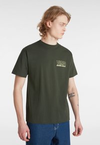 Oliven Grøn Bomulds T-shirt med Rund Hals, der har et lille gult Vans-logo på brystet. Klassisk lige pasform og korte ærmer.