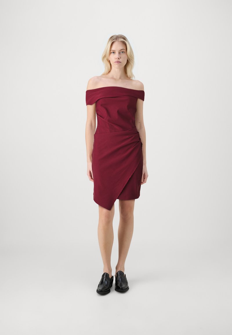 Burgundi off-the-shoulder mekko, jossa on tiukka keskiosa ja roikkuva, epäsymmetrinen helma. Yhdistetty mustiin kenkiin. Sileä kangas.