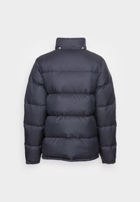 Chaqueta acolchada azul marino con un alto cuello, patrón acolchado horizontal, puños elastizados y acentos de botones a presión en el escote.