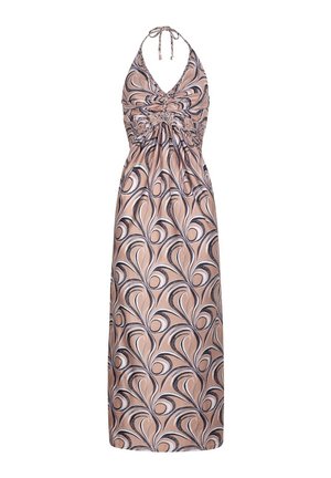 Mujer de pie en el interior vistiendo un vestido maxi sin mangas con diseños en espiral en tonos beige, negro y blanco.