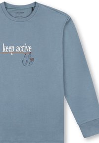 Felpa azzurro chiaro in cotone biologico con una grafica stampata di un bradipo e la scritta "keep active" in bianco e arancione.