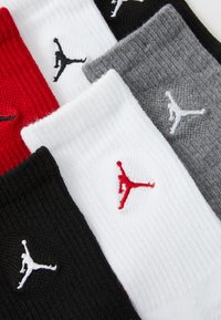 Fem par med ankelsokker i svart, hvit, rød og grå, med ribbestruktur og brodert Jumpman-logo.