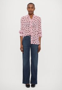 Light pink button-up blouse with red leaf print, paired with wide-leg dark blue denim jeans and black shoes. Smooth fabric, relaxed fit.