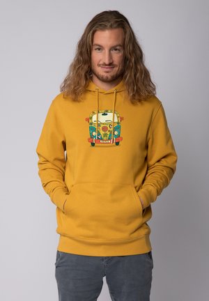 Gelbe hoodie met een voorzak, met een kleurrafische afbeelding van een bus en het woord "VREDE." Het heeft een capuchon met trekkoord en ribgebreide manchetten.