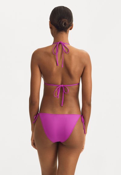 Bikini roz cu gât legat și închideri cu fundiță în partea de sus și pe laterale. Material neted, elastic, cu acoperire minimă și fără modele.