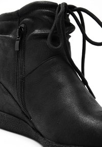 Bottine noire à la cheville avec fermeture éclair latérale, laçage sur le dessus et semelle texturée, en cuir lisse.