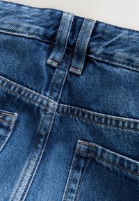 Blaue Denim-Jeans mit hohem Bund, orangefarbener Naht, zwei Gesäßtaschen und einer glatten Textur.