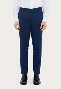 Marinblå byxor i texturerat tyg, slim fit, med rakt fram och sidofickor, kombineras med svarta skor och bärs tillsammans med en vit skjorta.