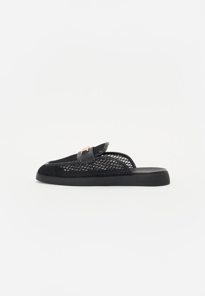 Sorte mesh slip-on sko med flad sål, dekoreret med en glat læderrem og guldhardware. Minimalistisk design med en tekstureret overflade.