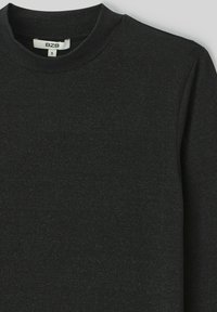 Chemise à manches longues noire en tissu doux, avec un col rond et une texture subtile. L'étiquette indique "B2B" avec une taille "S."