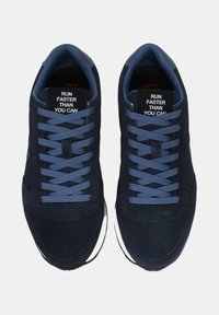 Sneaker blu navy con tomaia in suede, lacci piatti blu e suole bianche a contrasto. Le etichette all'interno leggono "CORRI PIU' VELOCE DI QUANTO PUOI."