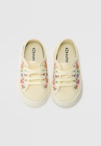 Kremfargede kanvas sneakers med blomsterbroderi i rosa, blått og grønt. Hvitt gummisåle med teksturert kant, rund tådesign.