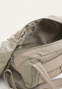 Väri beige selkäreppu, jossa on pehmeä, tikattu pinta ja tilava tyhjät sisäosa. Varustettu säätötuilla harteilla ja turvallisella vetoketjulla.