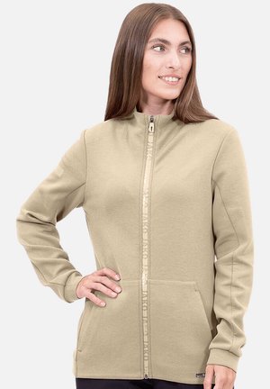 Sweat à fermeture éclair beige avec col montant, poignets côtelés, poches avant et détails réfléchissants sur la fermeture éclair. Texture de tissu lisse avec un design ajusté.