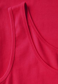 Top de tirantes de algodón rojo con tirantes anchos, textura suave y costuras sobrehiladas. Enfocado en la comodidad y el ajuste.