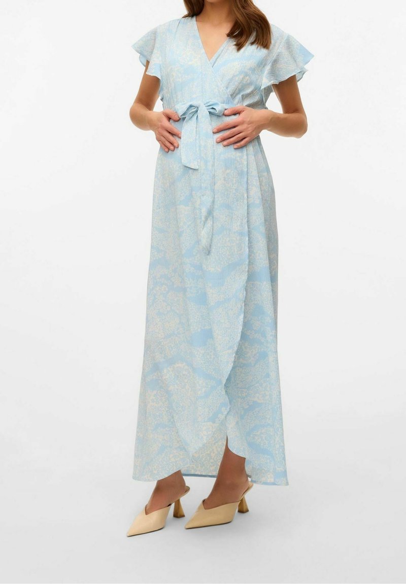 Abito avvolgente azzurro chiaro con maniche corte a volant, motivo floreale in crema, fissato con un nastro in vita. Abbinato a tacchi beige chiaro.