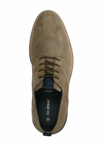 Bruine suede schoen met een vetersluiting, geperforeerde textuur, contrasterende lichte stiksels en een zwarte binnenzool met de tekst "geen stress."