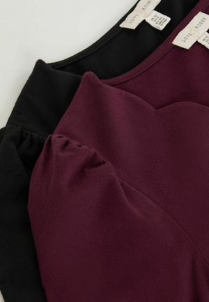Topuri din țesătură neagră și burgundă cu o textură moale, având mâneci bufante și un decolteu curbat. Etichetele sunt vizibile la spate.