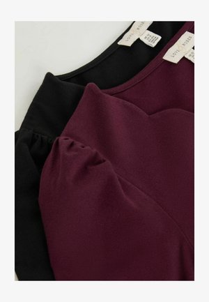 Topuri din țesătură neagră și burgundă cu o textură moale, având mâneci bufante și un decolteu curbat. Etichetele sunt vizibile la spate.