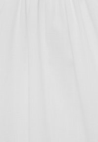 Tissu blanc avec de subtiles plis verticaux et une texture douce, éclairé uniformément sans motifs ni objets visibles.